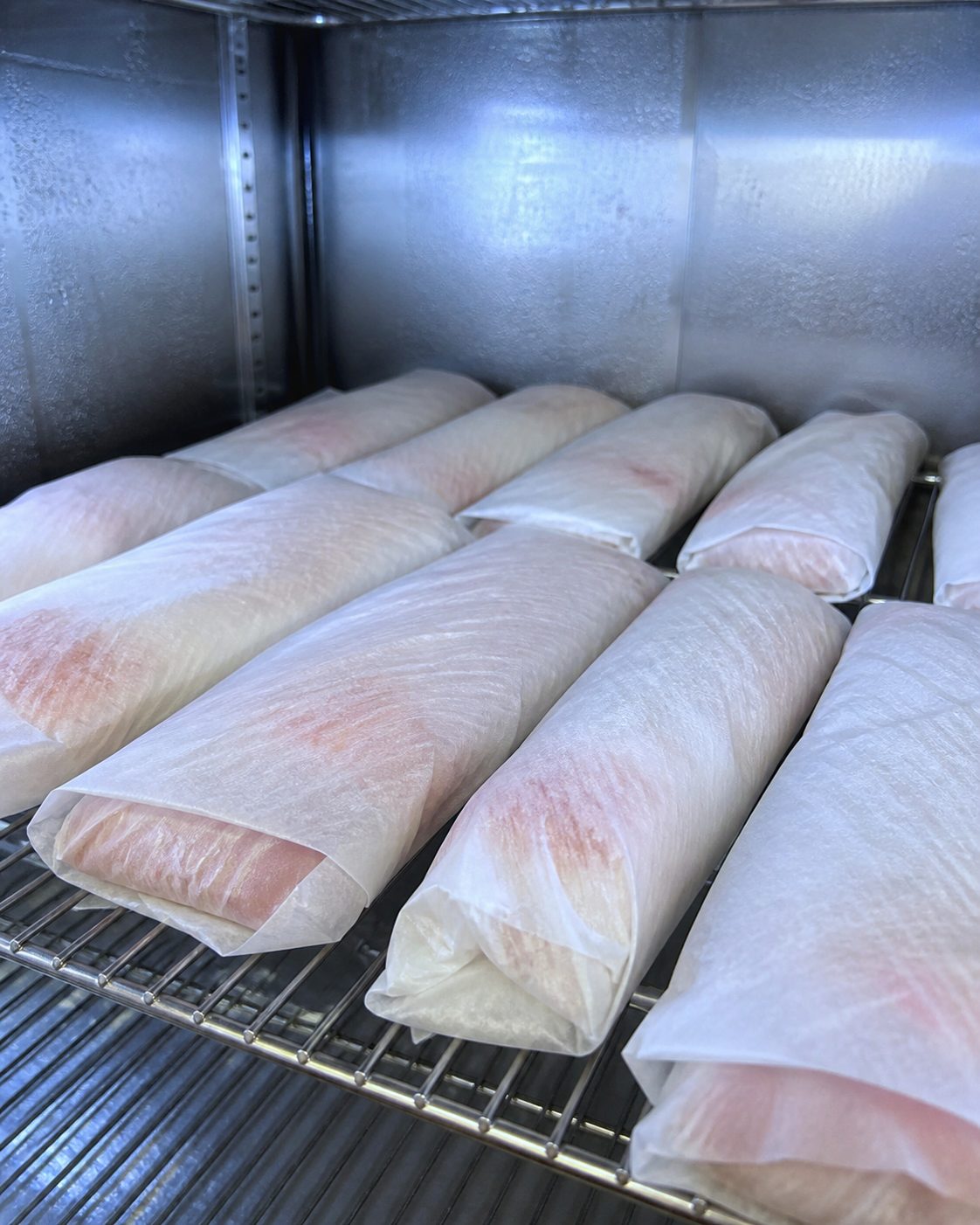 低温の熟成庫に整然と並べられた、和紙に包まれた魚の柵