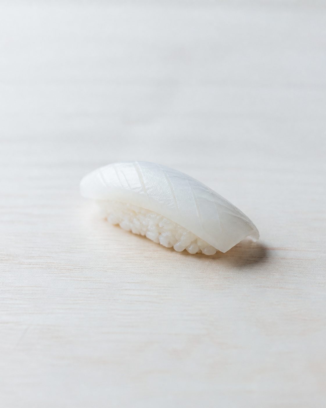 白木のカウンターの上に一貫だけ置かれた握り鮨