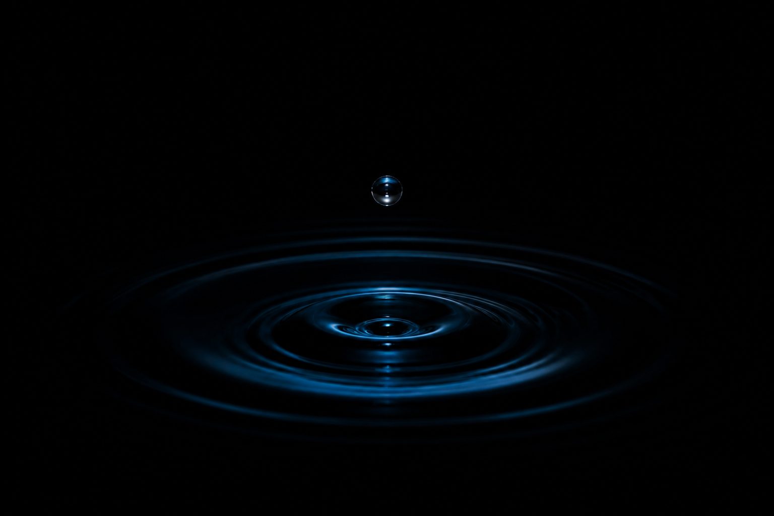 黒い水面に落ちる一滴と同心円の波紋