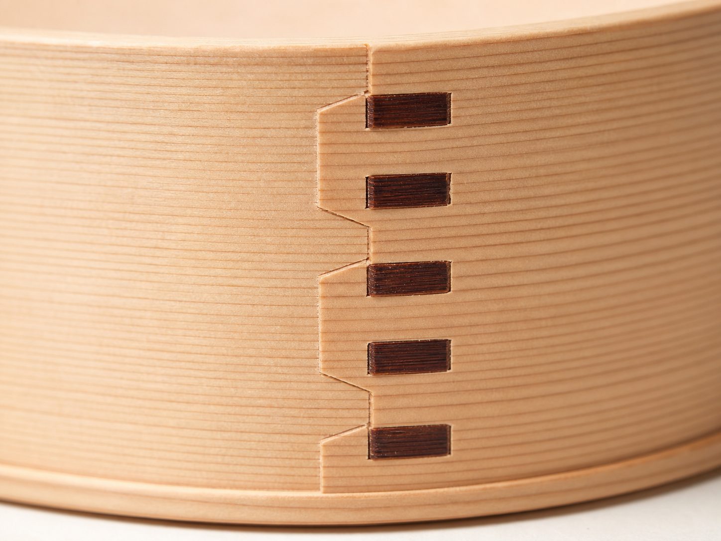 曲げわっぱ側板の接写。桜皮の綴じ目とまっすぐな柾目が見える