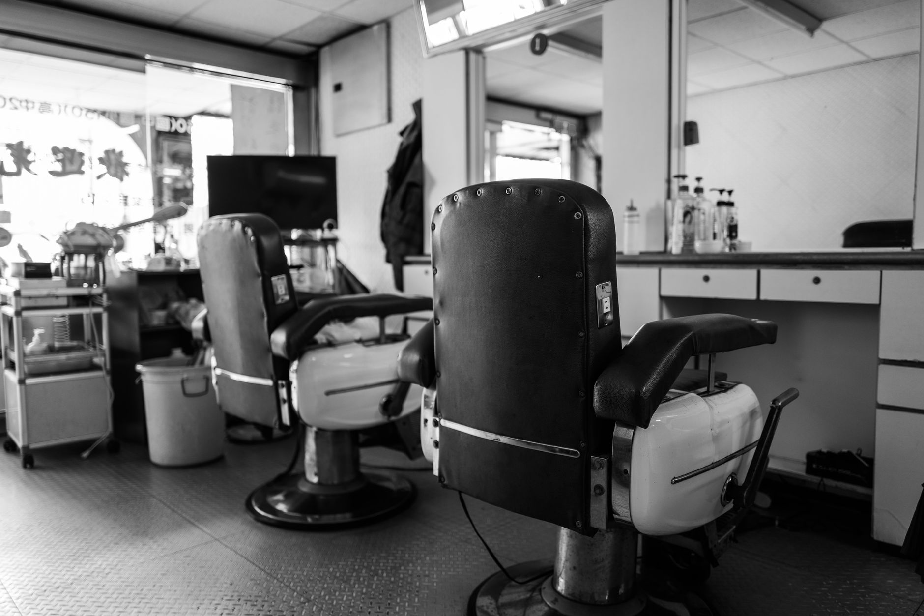 真鍮の什器と革のチェアが並ぶ薄暗いバーバーの店内